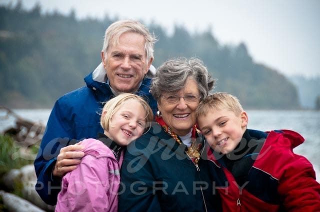 two grandparents posing with their two grandchildren next to a waterfront
