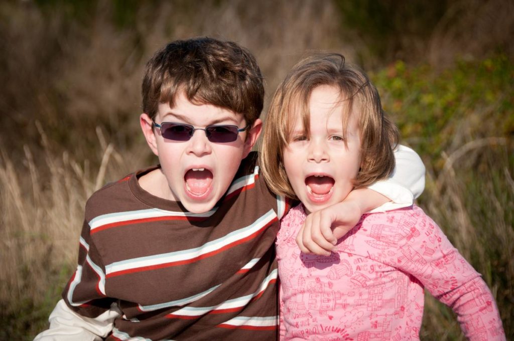 young boy in brown shirt and glasses with his sister in a pink shirt