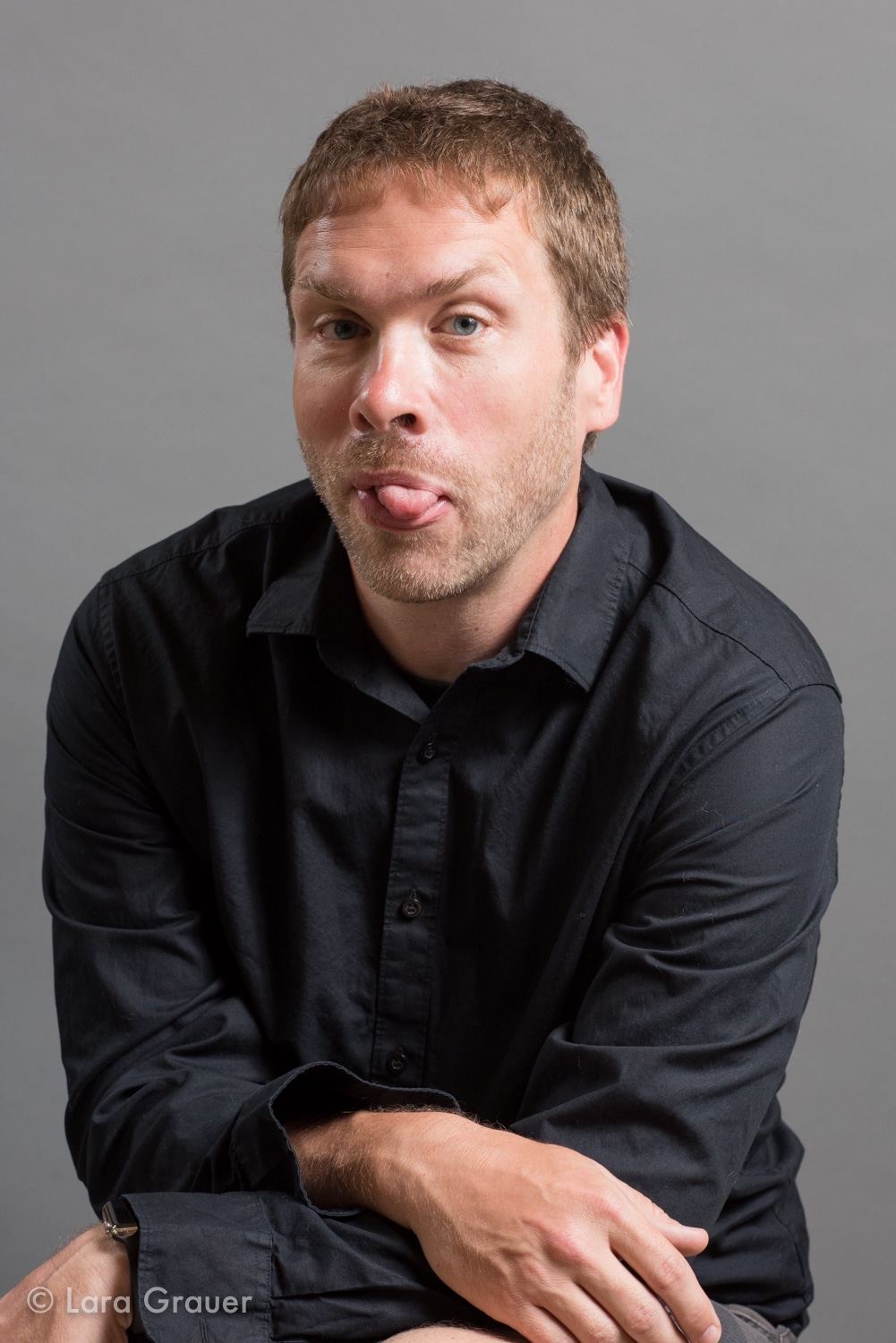 photo of a man in a black button down shirt sticking his tongue out