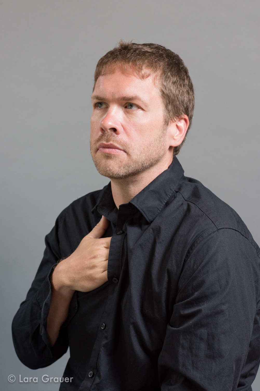 man in a black buttoned down dress shirt with a hand inside of it.