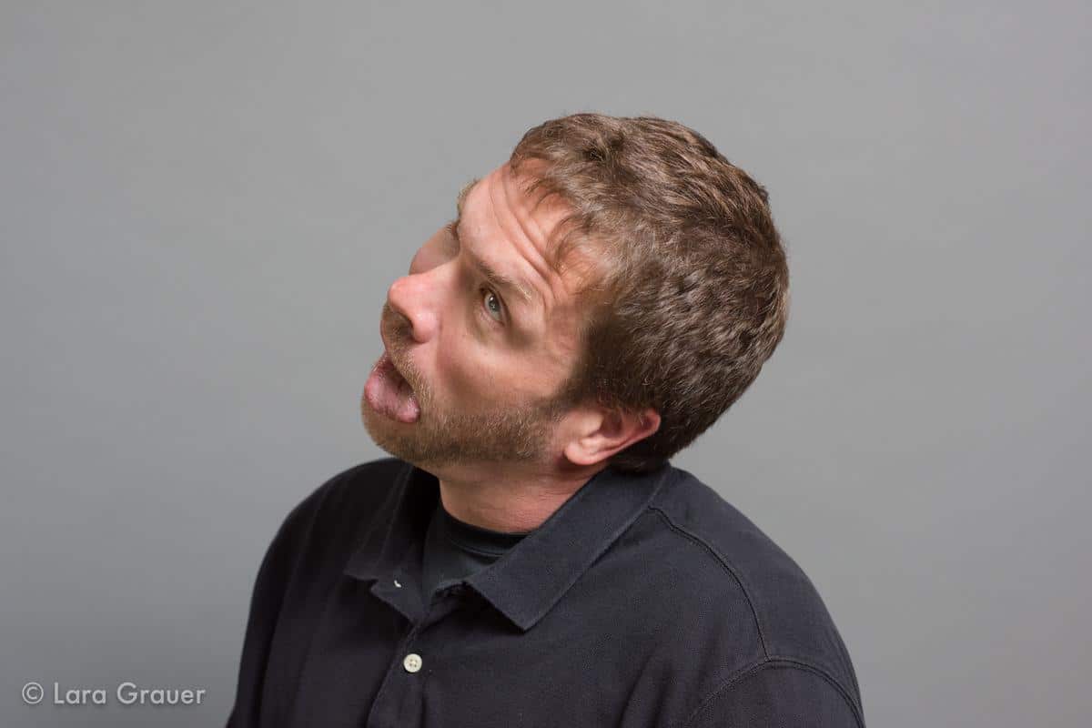 man in a black polo shirt making a funny face gesture.
