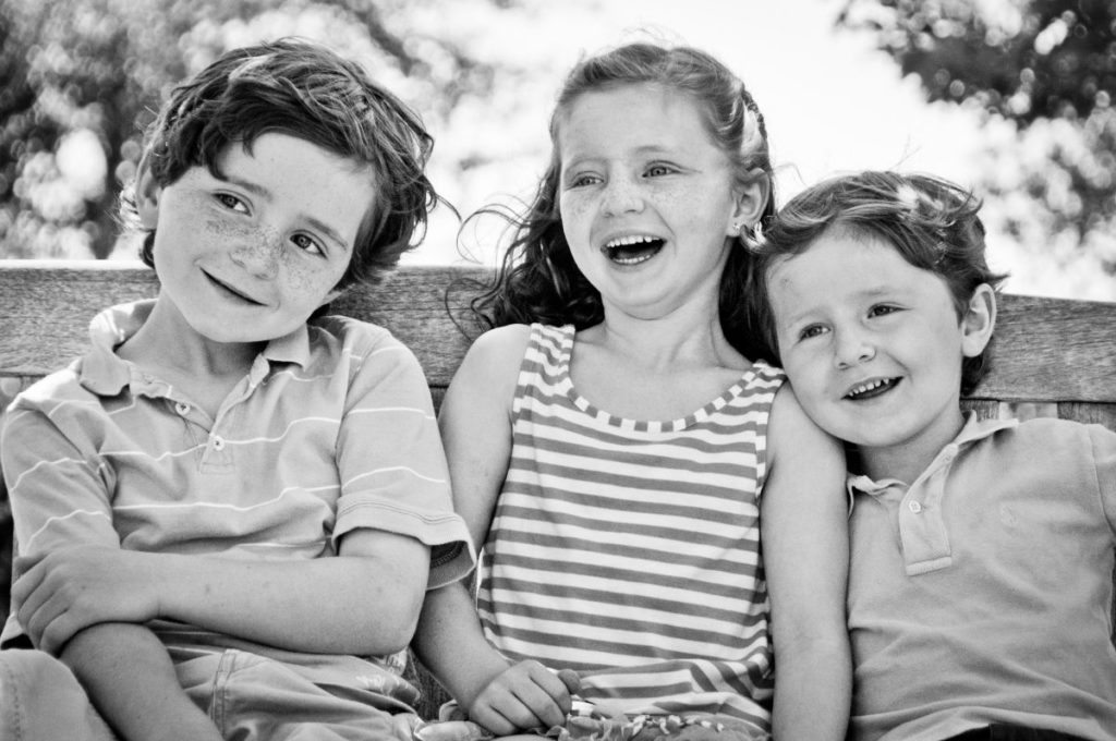 Portrait of 3 siblings laughing in 2011