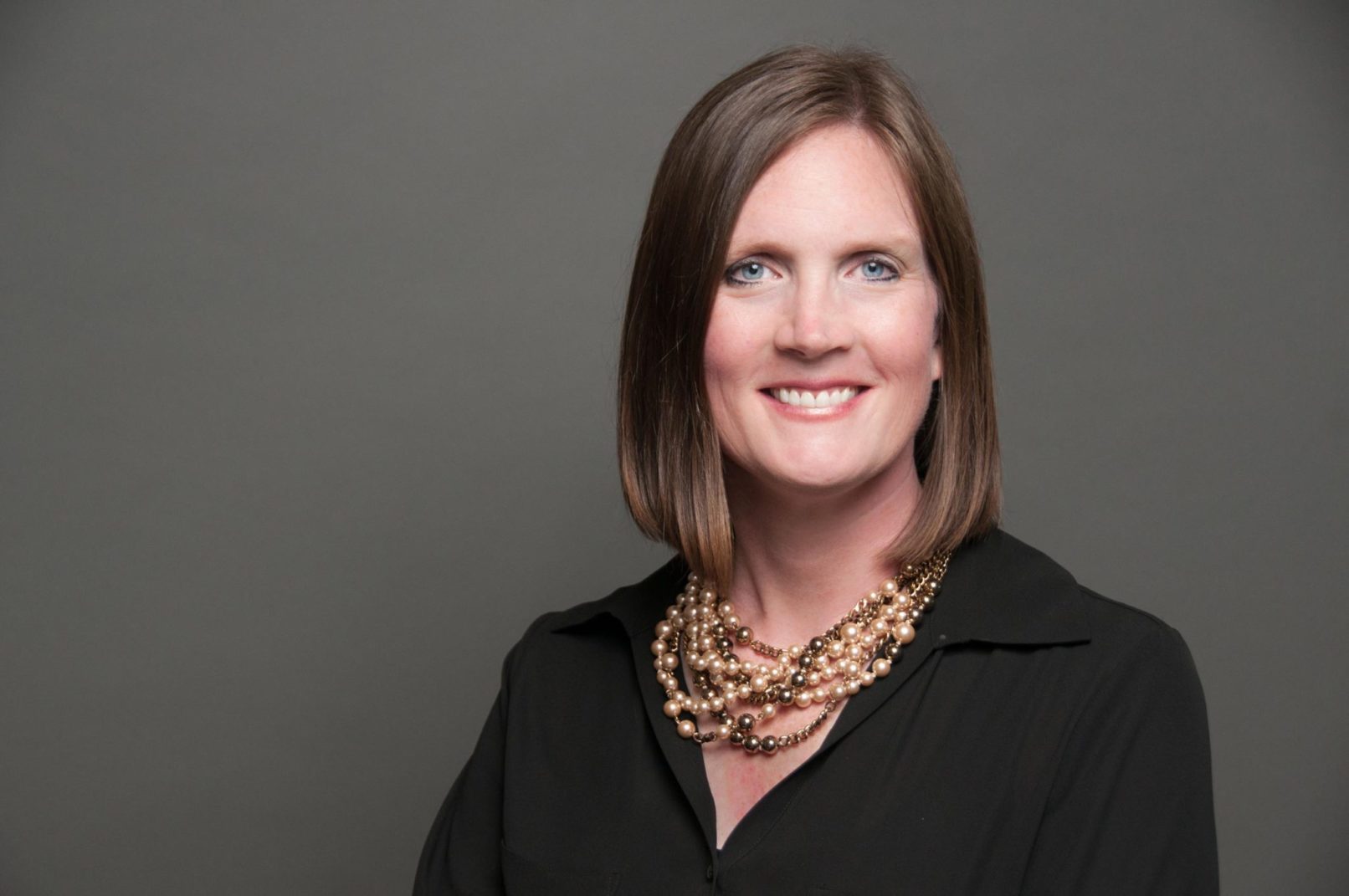 business headshot of a female executive coach with a pearl necklace and black top.