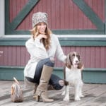 women in cheetah print hat kneeling and posing with her brown bag and white and brown bag dog.