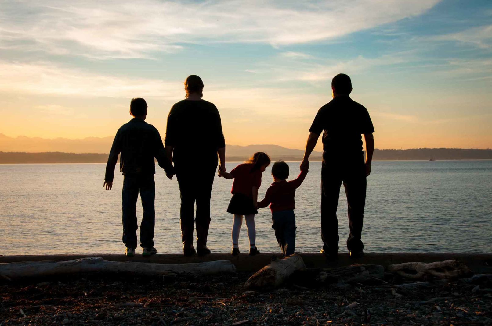 family portrait silhouette in the sunset overlooking a waterfront.