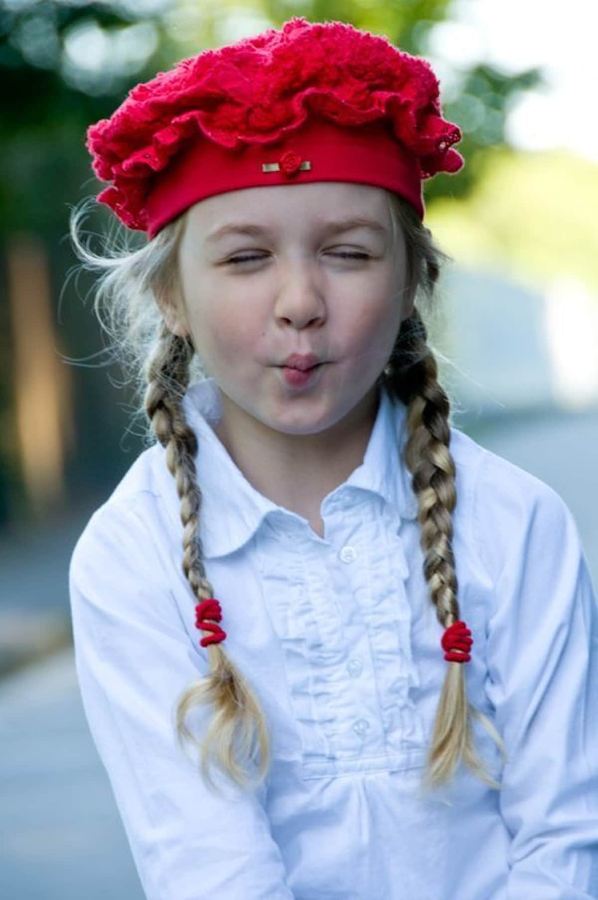 young blonde girl with ponytails wearing a red hat.
