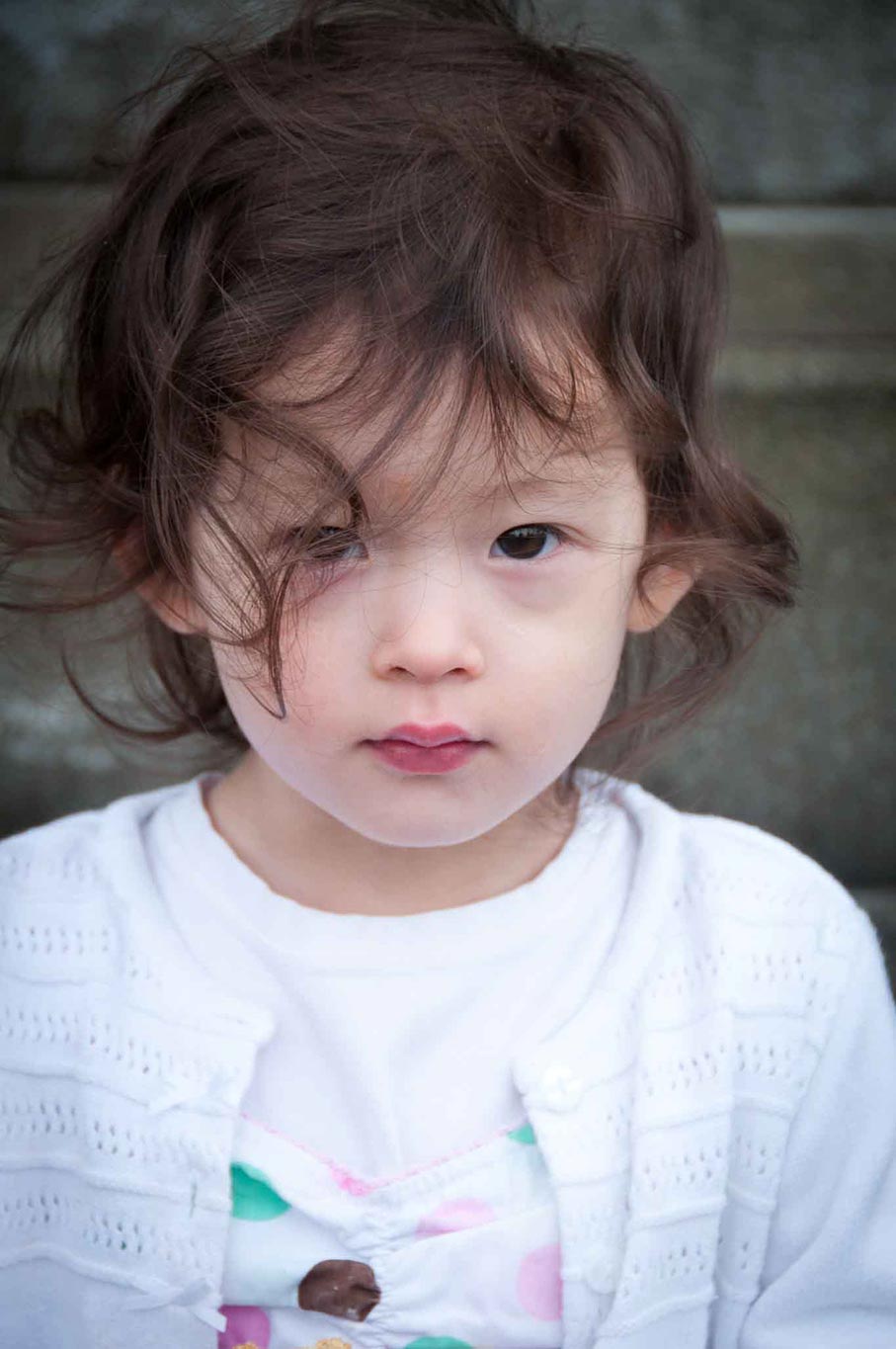 portrait of little girl with a piercing gaze in white sweater.