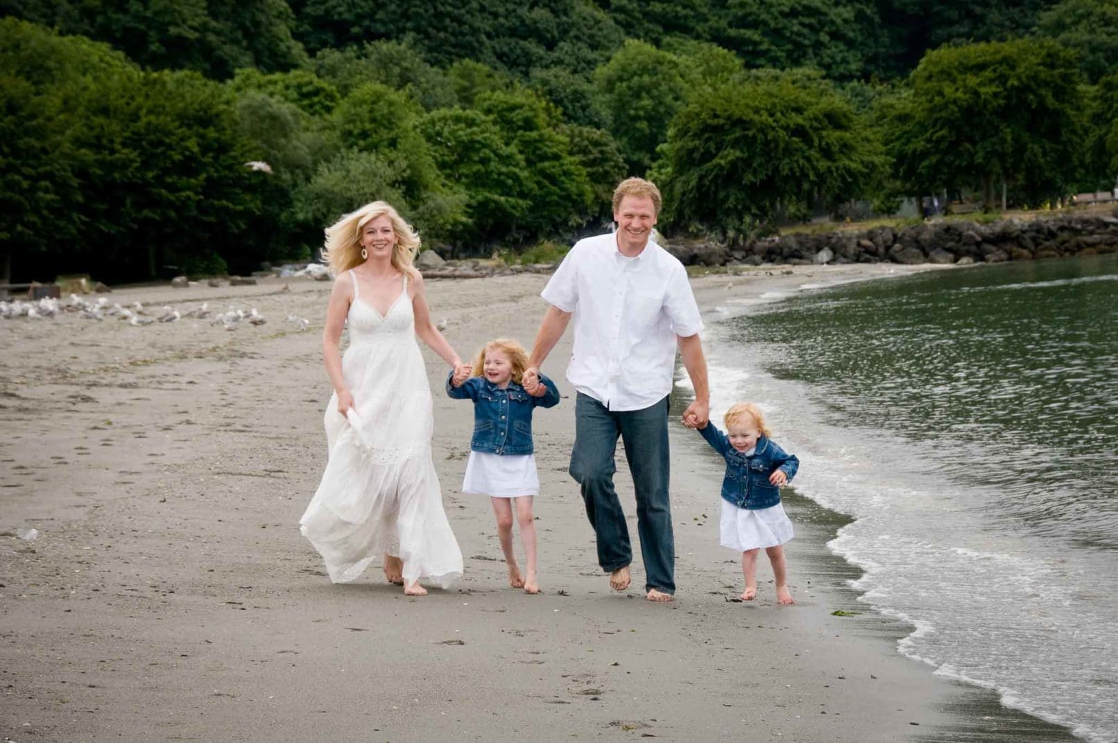 Family Photo Of Parents Holding Hands With Children While Walking Down Beach By Seattle Photographer Lara Grauer Photography