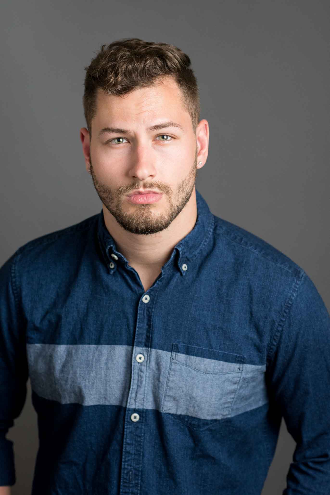 promotional headshot of male actor wearing a denim button up shirt.