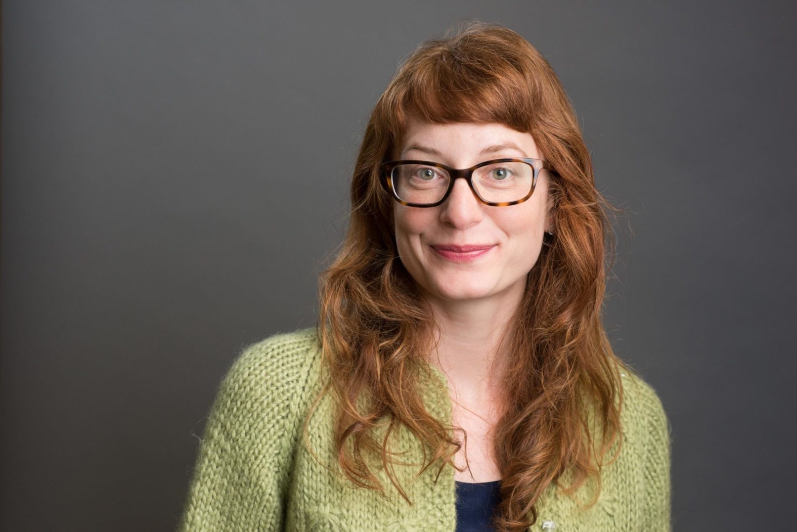 business headshot of a senior female landscape architect with glasses and green sweater.