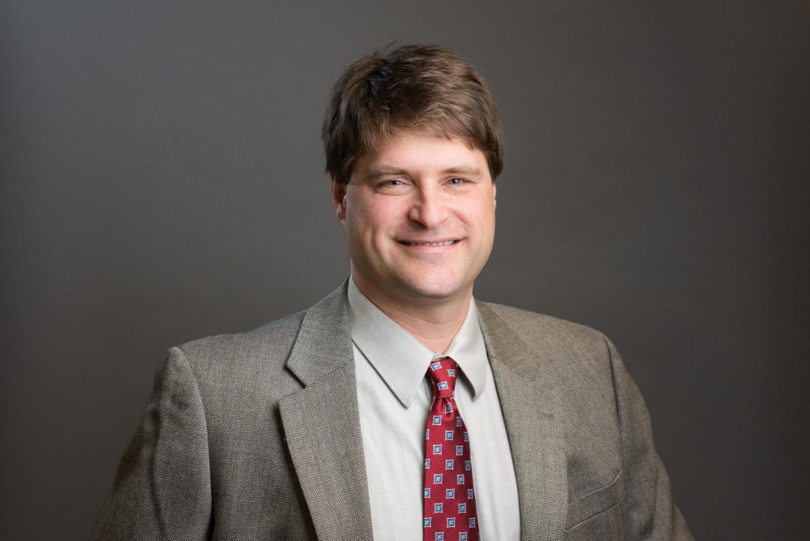 business headshot photo of male professional wetland scientist in a grey suit with a red tie.