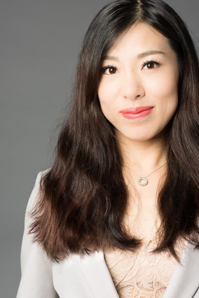 women with long dark brown hair and formalwear smiling towards the camera.