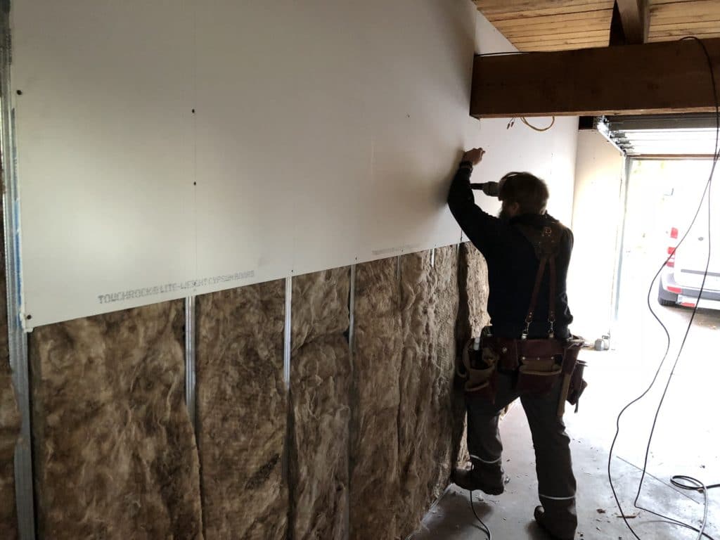 man working on an unfinished dry wall.