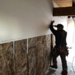 man working on an unfinished dry wall.