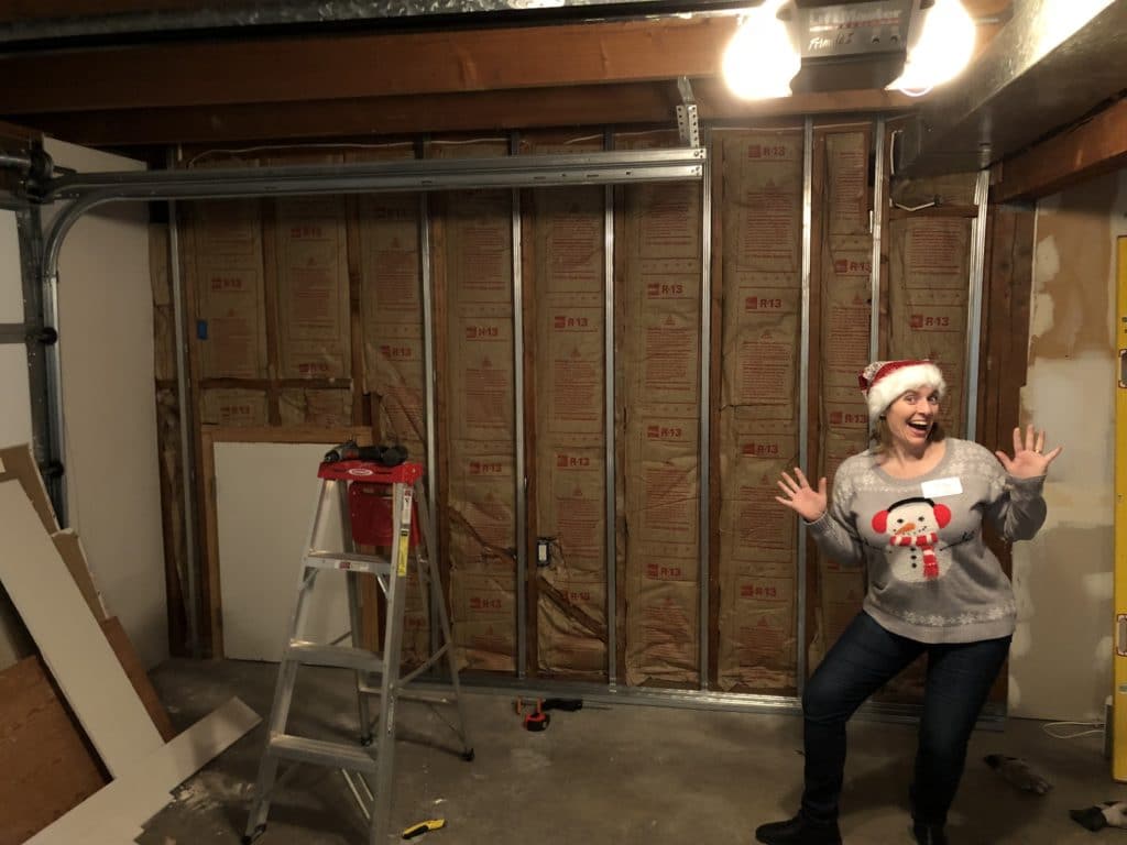 woman excitedly posing in front of an unfinished wall.