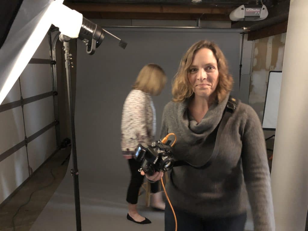 women with dslr camera working on a photo shoot in an unfinished photography studio.