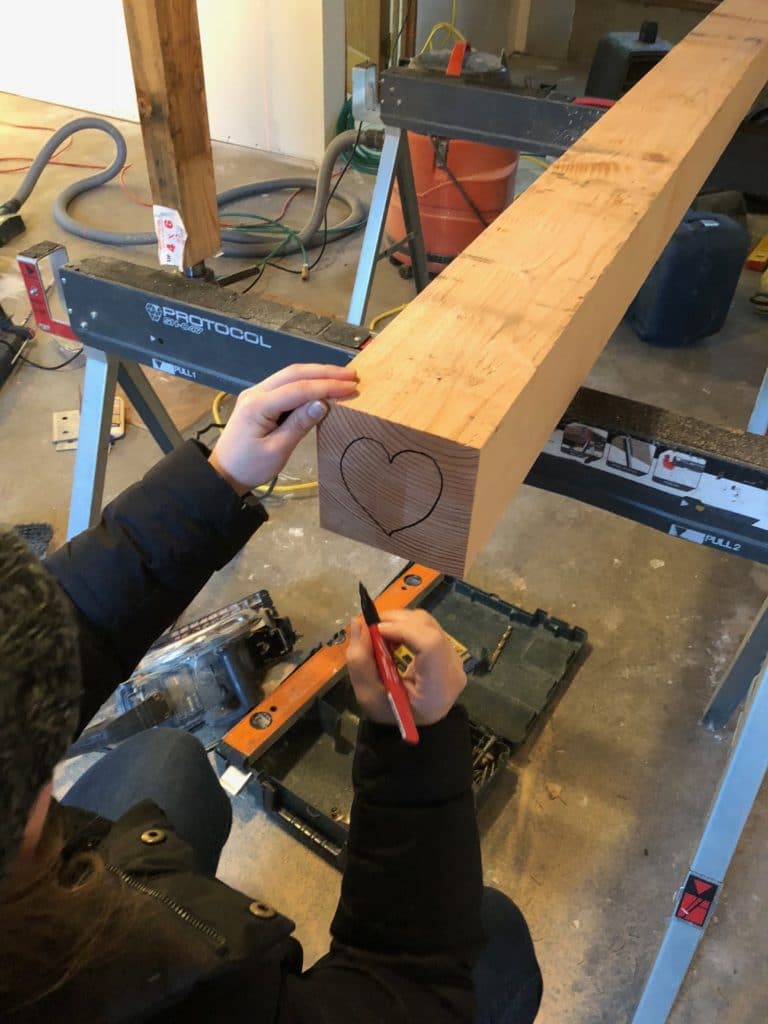 photo of a woman drawing a heart on the bottom of a post.