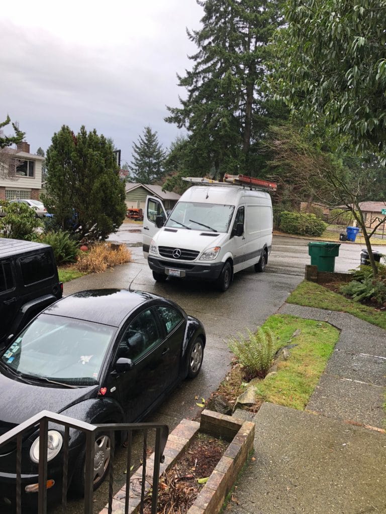 driveway with black vw beetle and a white medcades-benz work truck.