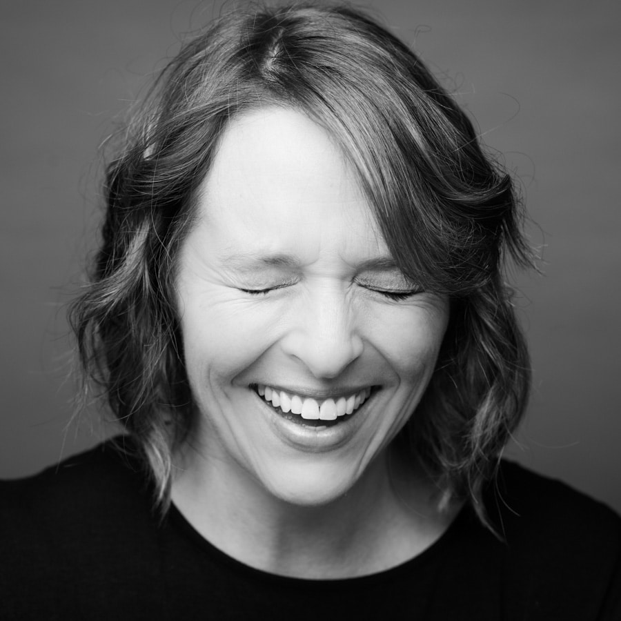 black and white headshot photo of woman laughing with her eyes closed