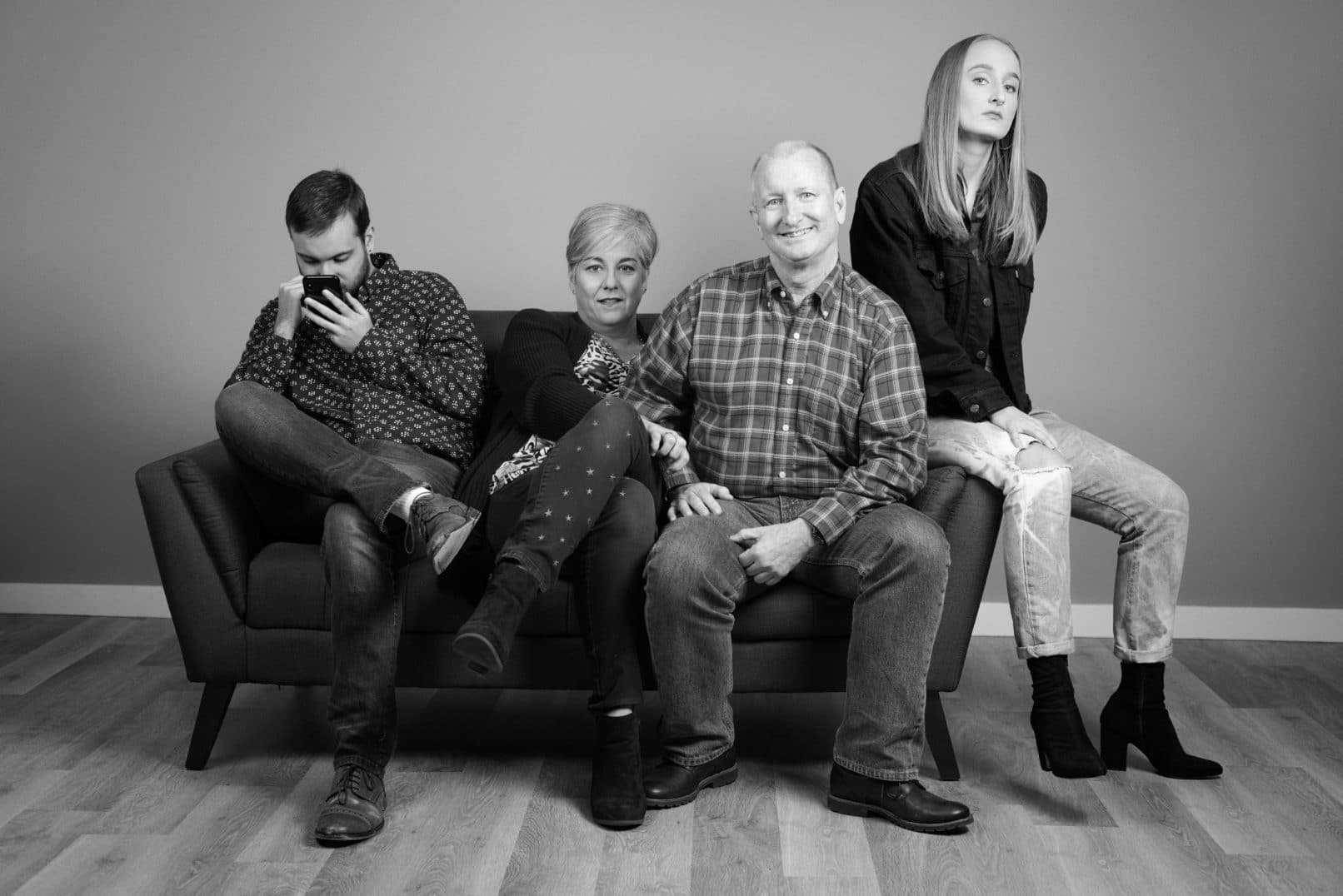black and white studio portrait of family of four on sofa
