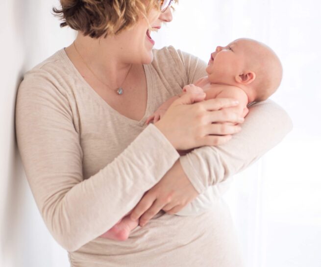 mother holding her new born baby and laughing