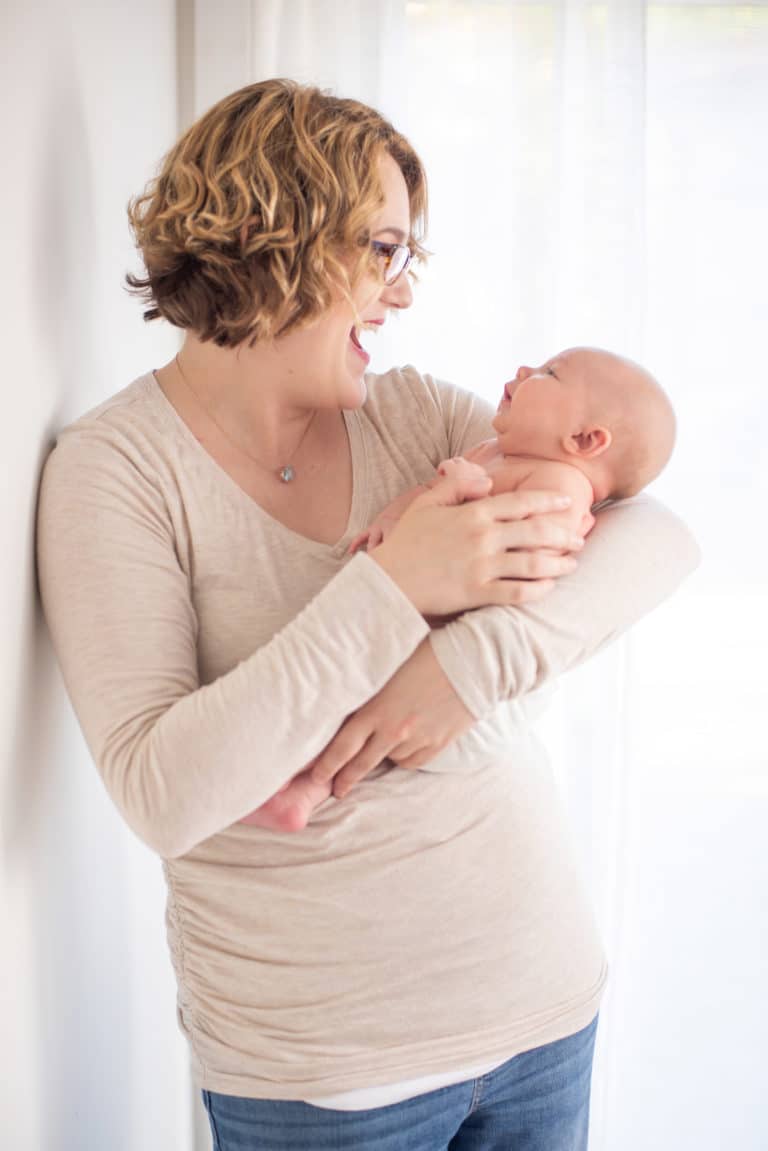 mother holding her new born baby and laughing