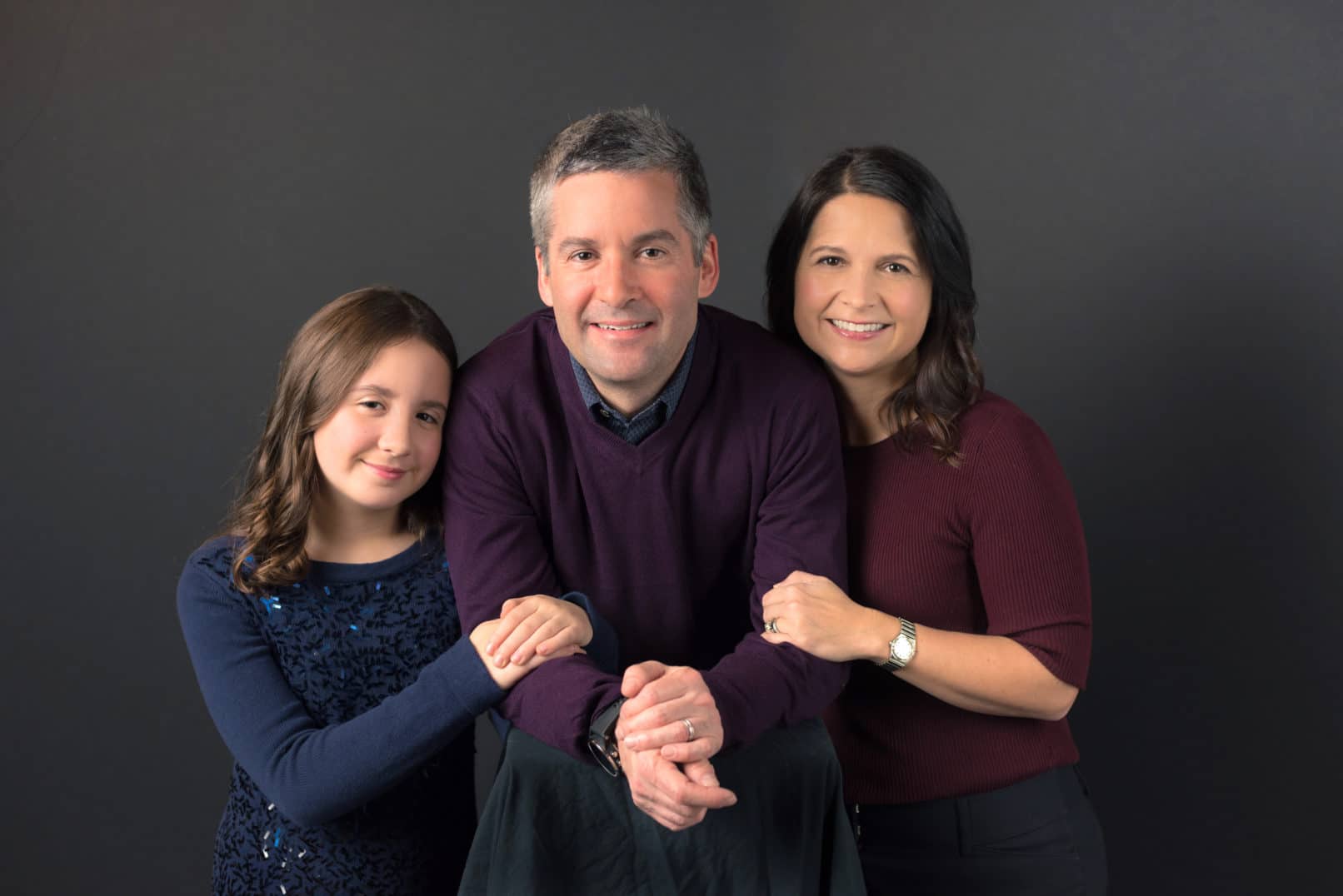 professional studio family portrait of father, mother and young daughter.
