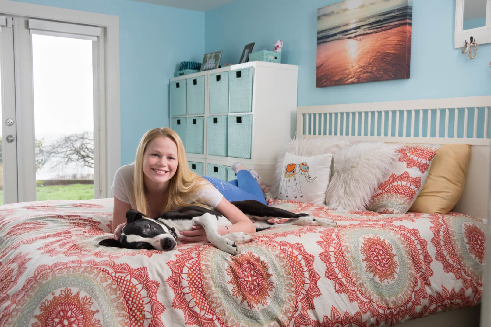 portrait of high-school senior girl with her dog on a bed