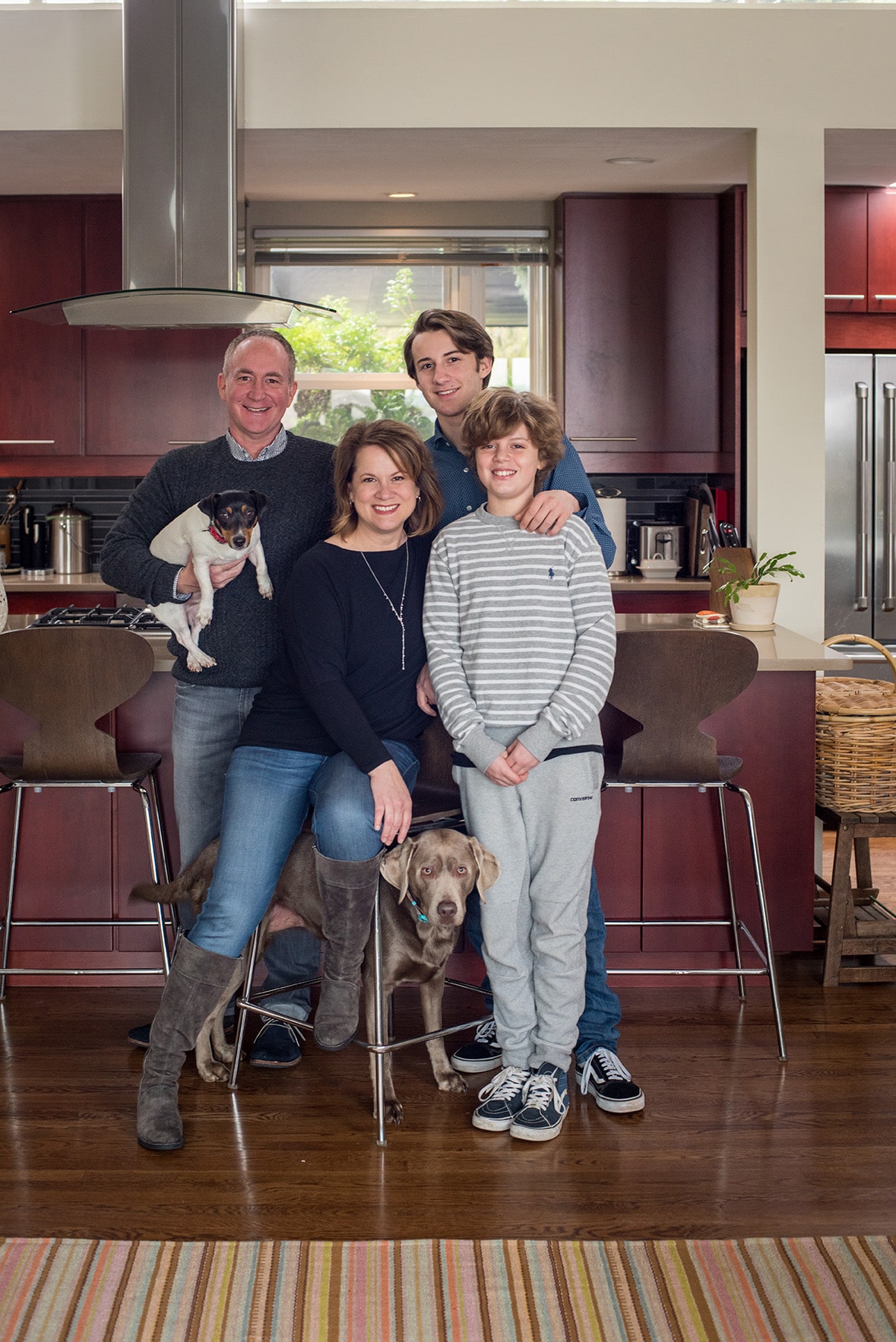 family portrait of a mom, dad, and two sons with their two dogs in the kitchen