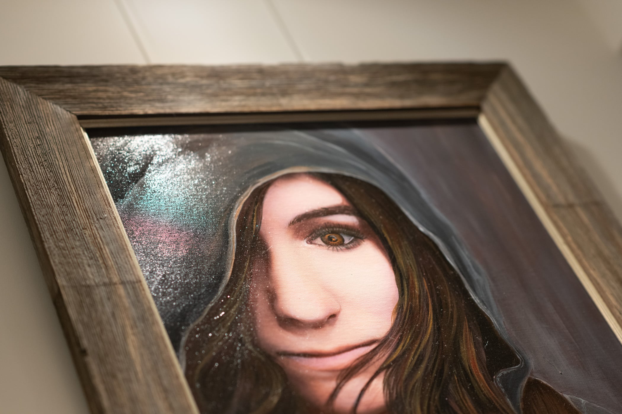 Painting of a partial face of a woman with something covering head. that looks like a jacket or rain coat.