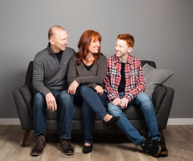 studio portrait family of a mom, dad, and son on the couch