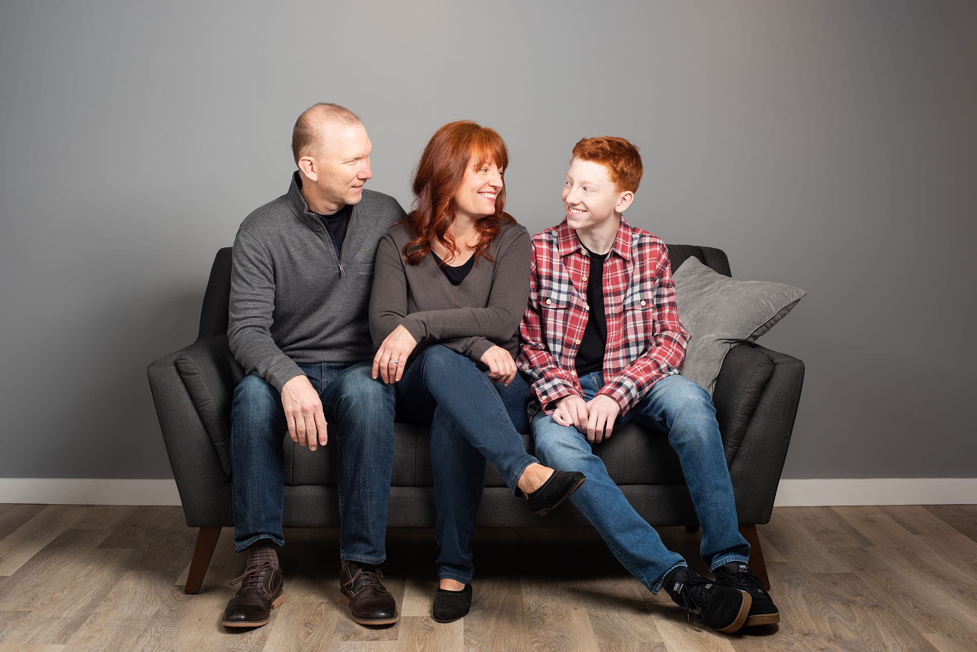 studio portrait family of a mom, dad, and son on the couch