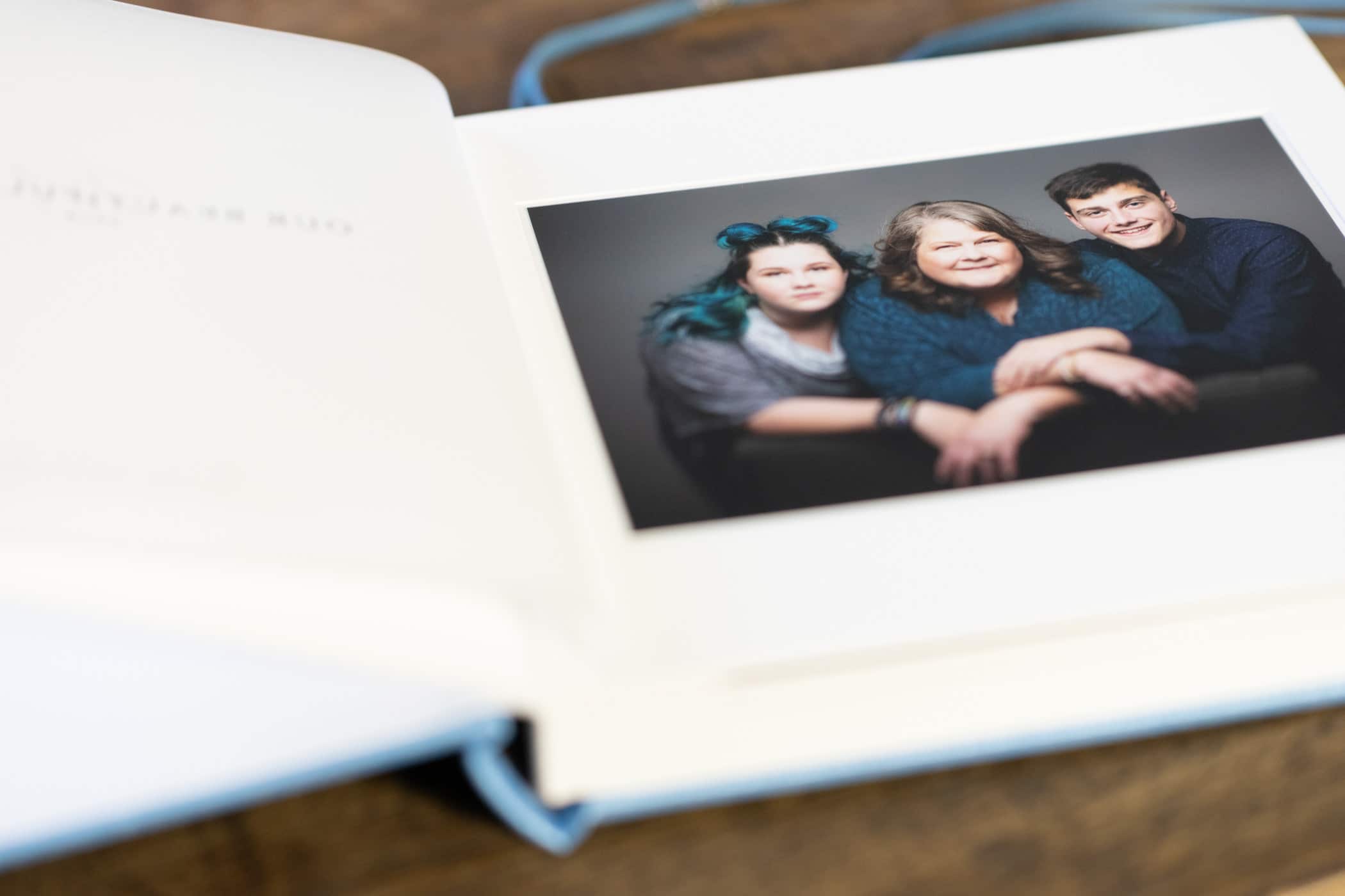 close-up of a photo album page displaying a family portrait with mother and two children, one on each side.