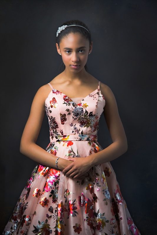 young woman staring into camera wearing a flowered gown.