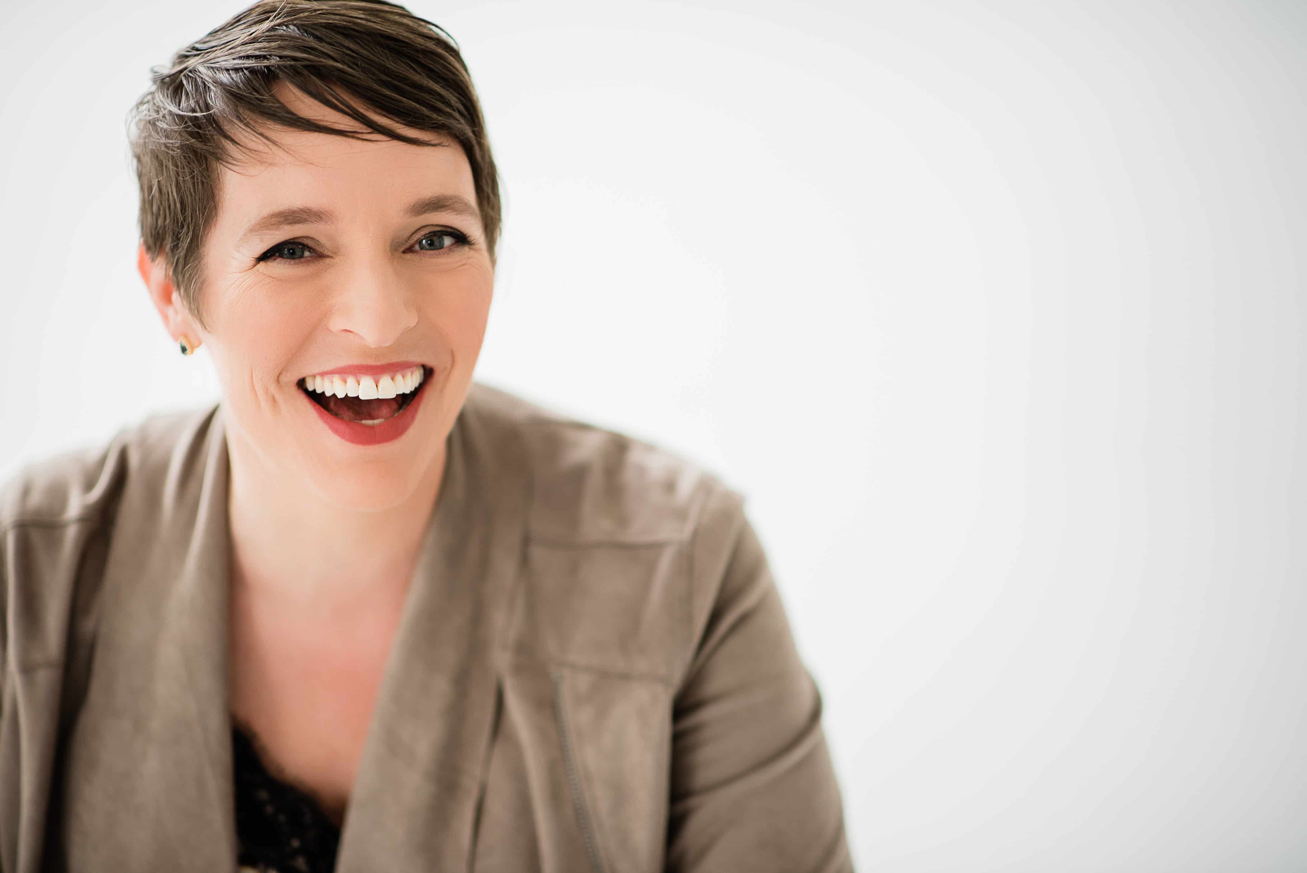 woman laughing in front of a white backdrop.