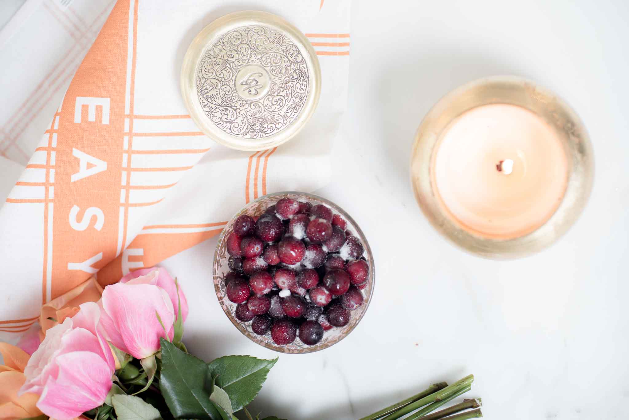 table with roses, candle and sugar frosted bowl of cheeries.