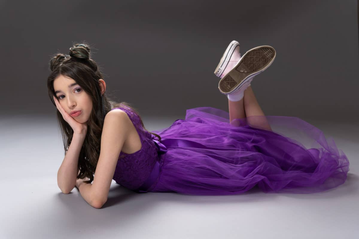 Portrait of a girl laying down with a purple dress and sneakers