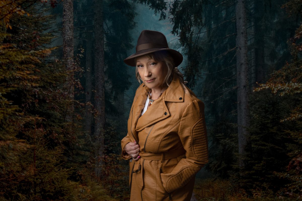 Female dressed in detective type clothing exploring in the woods.