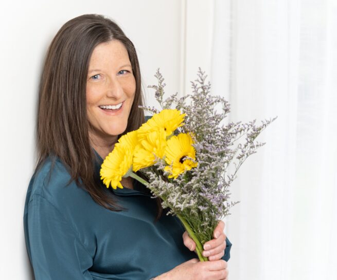 Portrait of woman smiling and holding flowers.