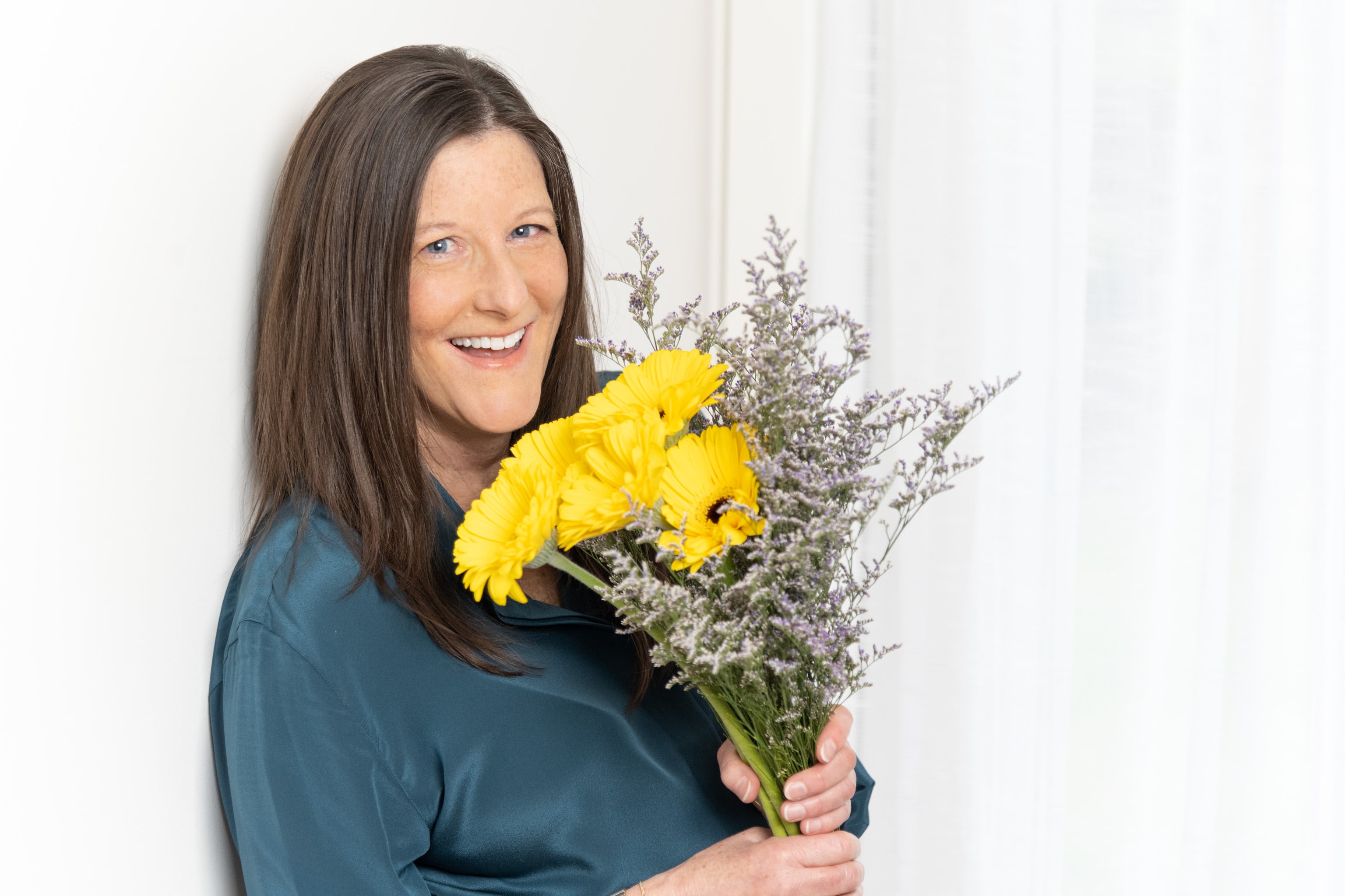 Portrait of woman smiling and holding flowers.