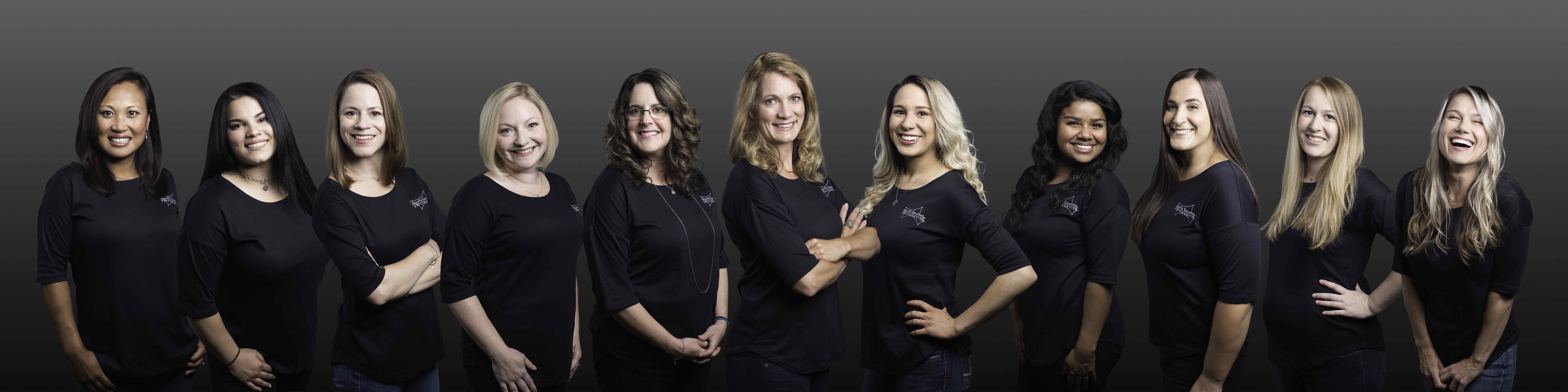 Group composite photo of 11 women posing for the camera in black shirts.