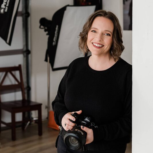 Photographer holding camera in studio while smiling