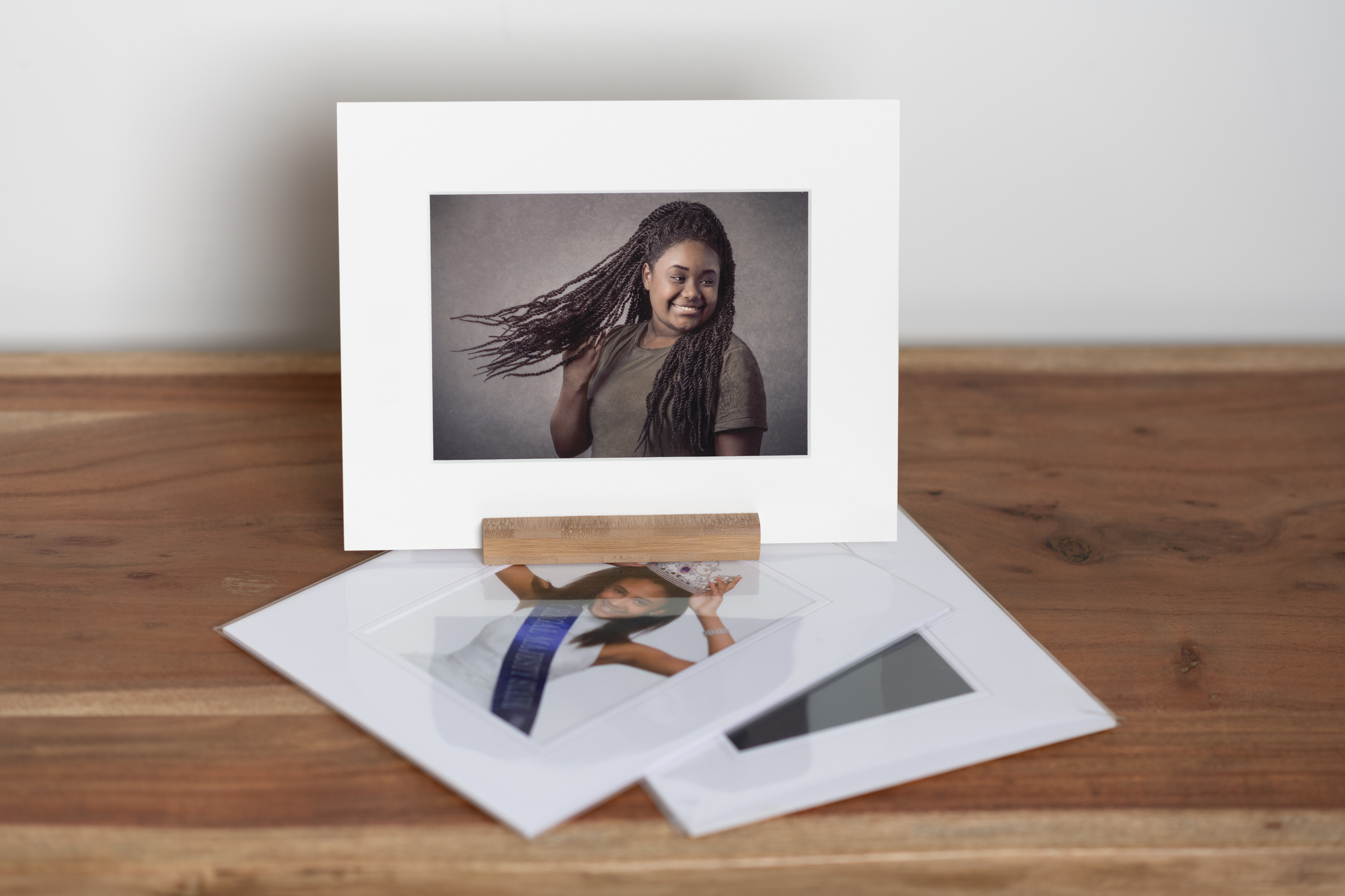 Matted gift photos displayed on wood table with white wall background.