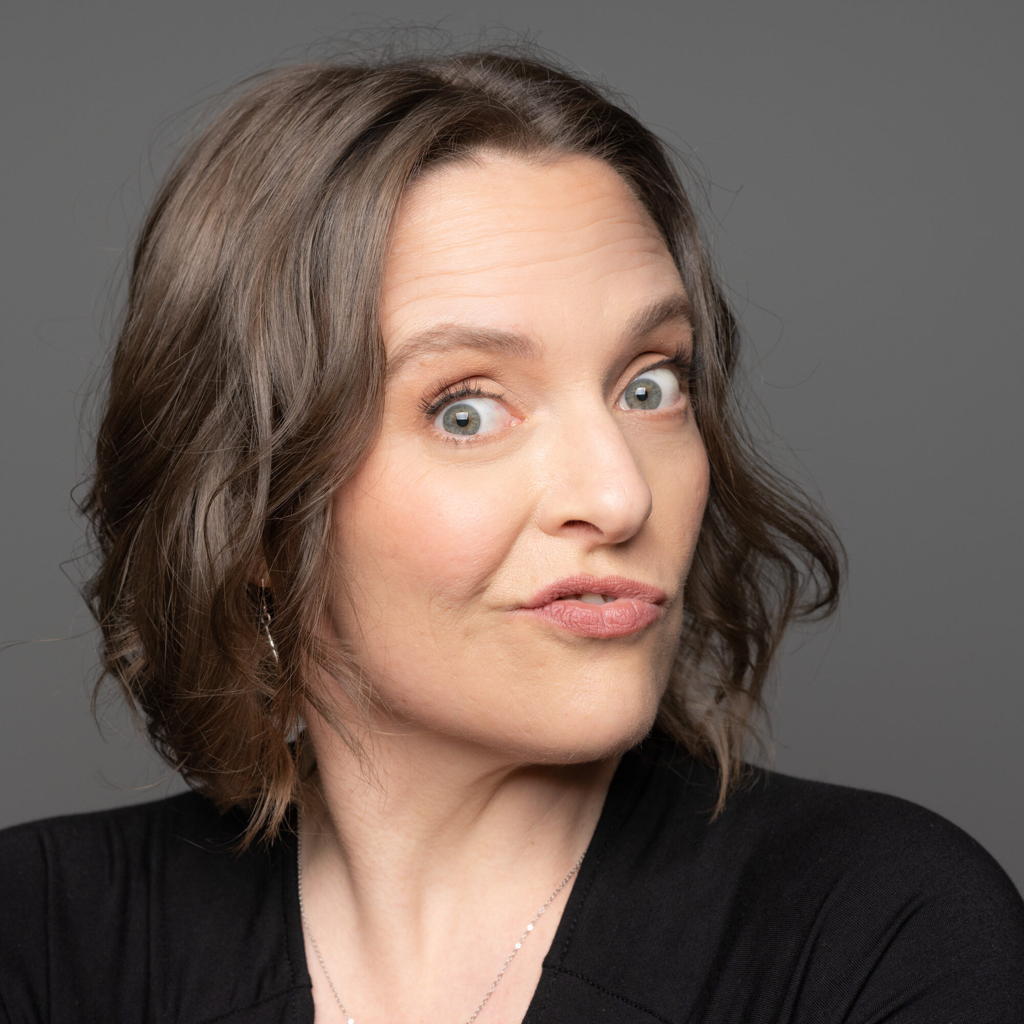 headshot photo of a brunette woman making a silly face towards the camera