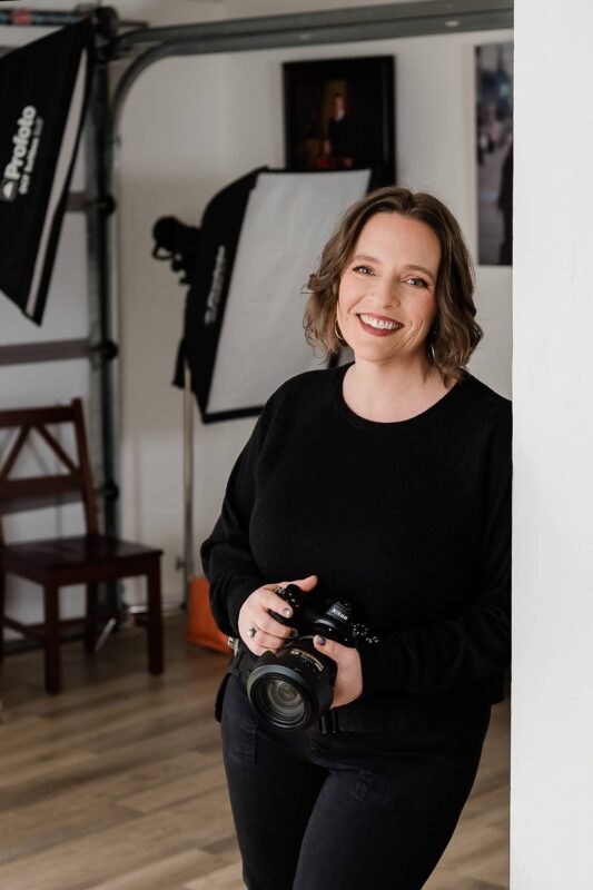 Lara Grauer holding camera in studio while smiling