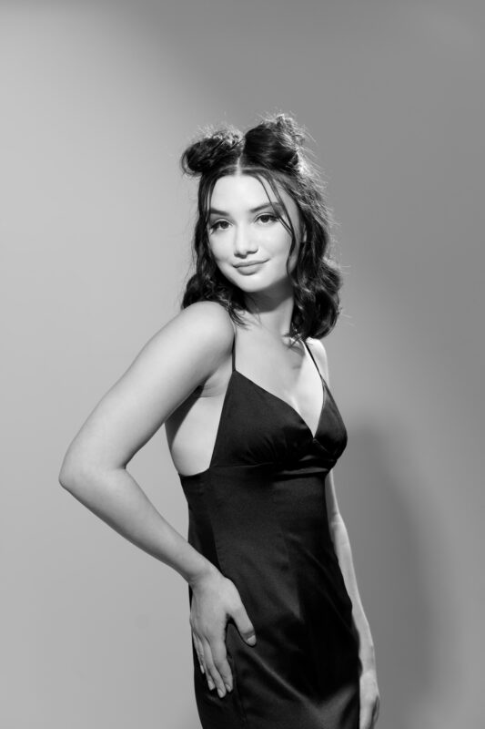 Young woman posing wearing a black dress .