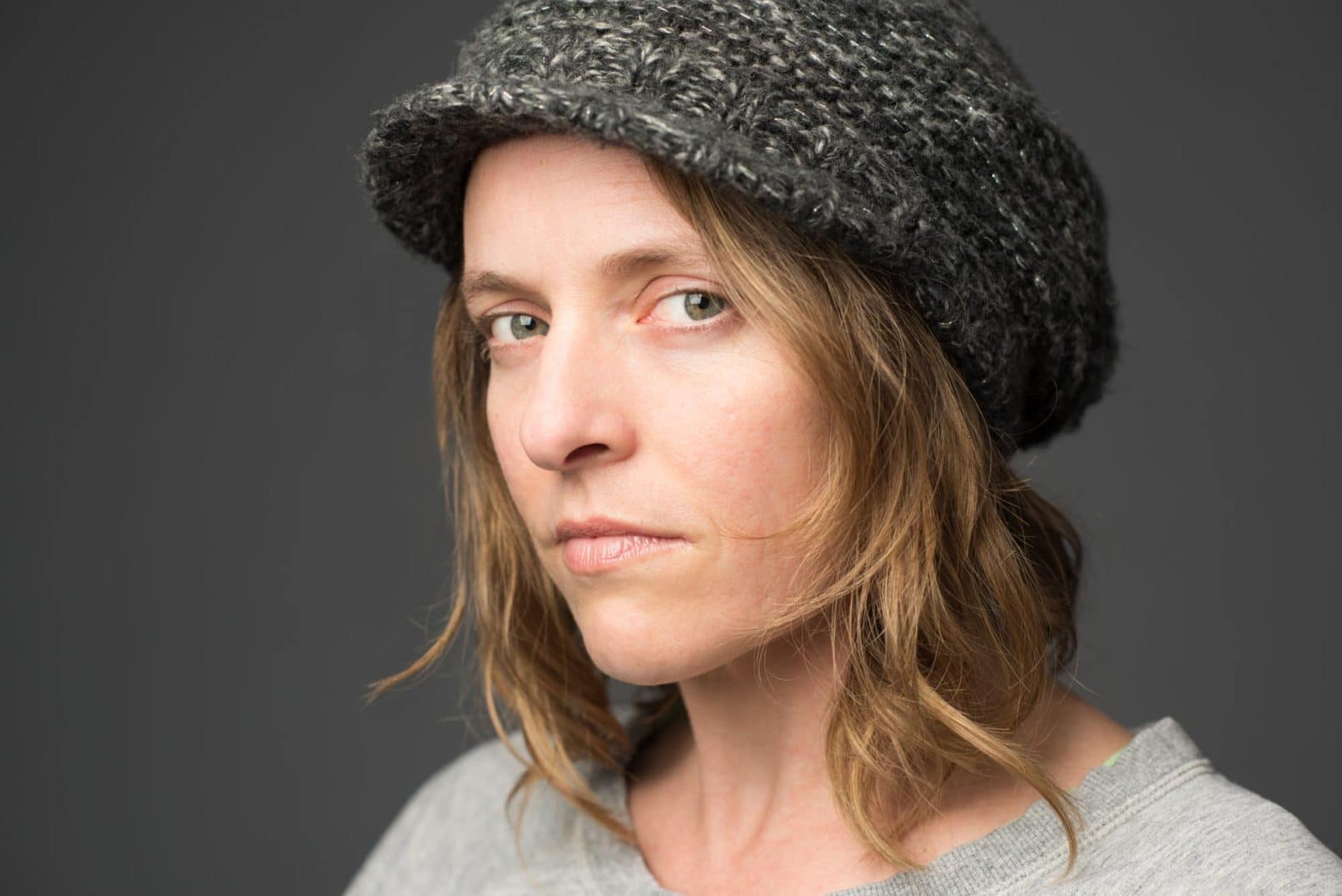 Close-up of woman wearing a wool hat, staring at camera.