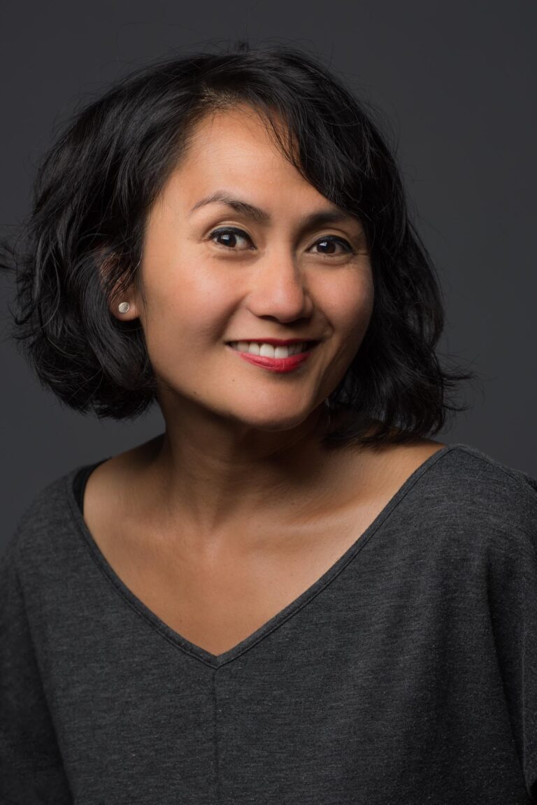 Woman wearing a gray top, posing for headshot.