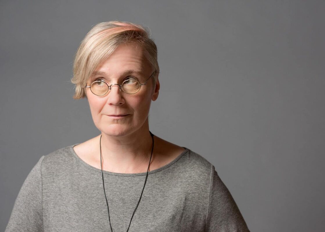 Headshot of a woman wearing glasses and eyes looking to the side while facing forwards.