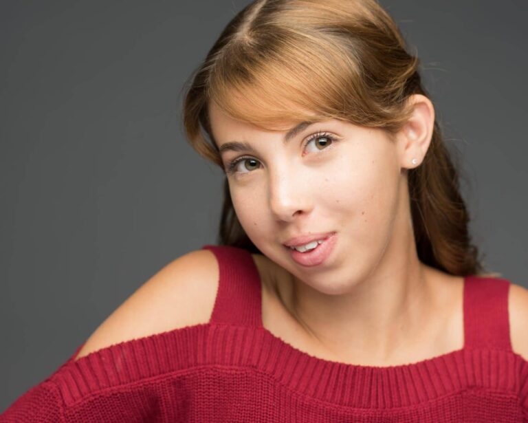 Woman wearing a red sweater. posing for headshot.